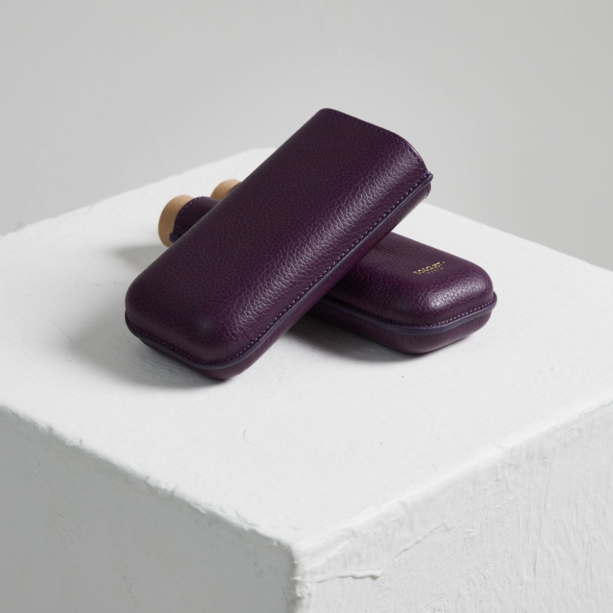 Two Bosquet Smooth Purple Leather Cigar Cases on top of a white cube.
