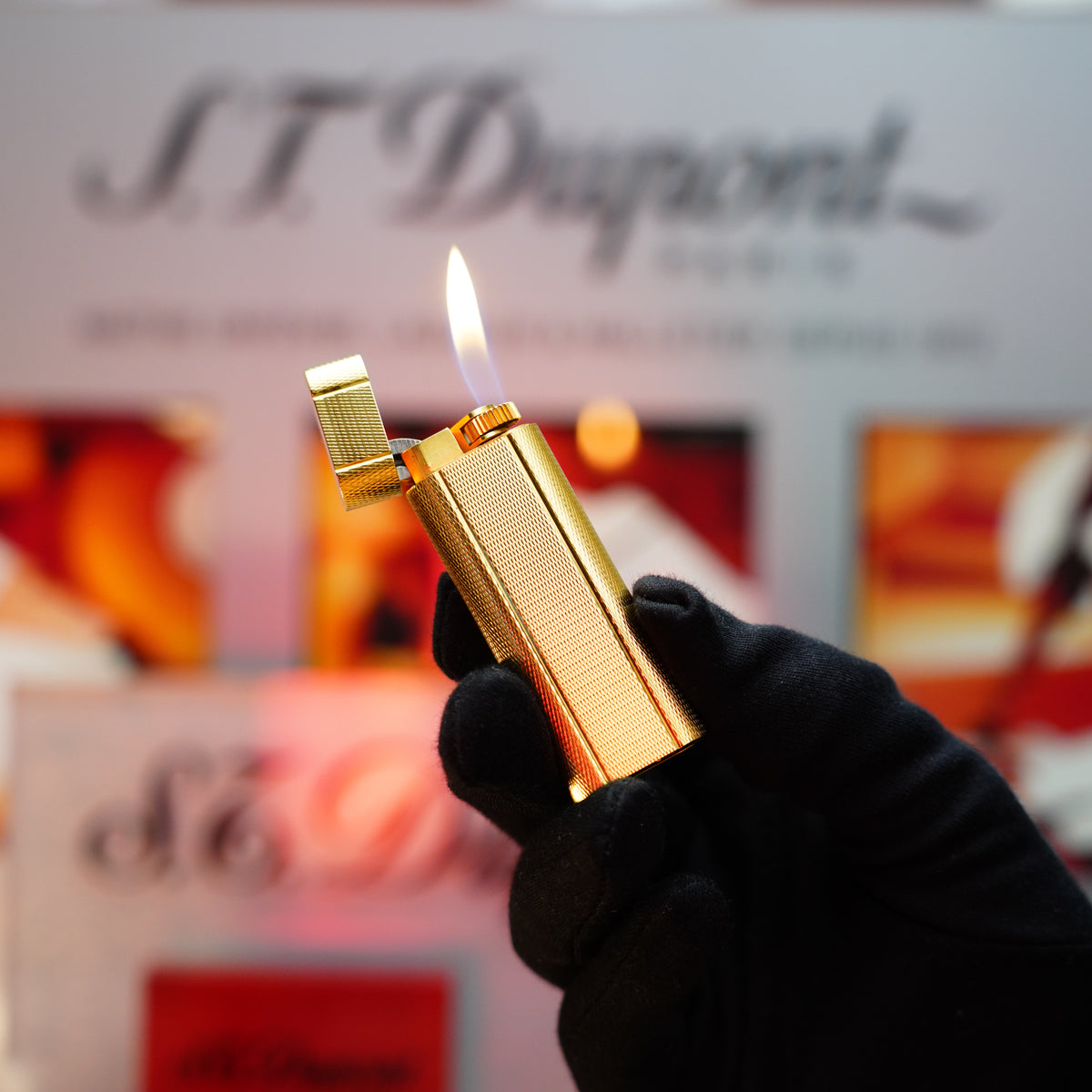 A gloved hand elegantly holds a Vintage 1980 Cartier Le Must Fine Hobnail & Lines Pattern Lighter, its 24k gold finish shimmering against a blurred background with text.