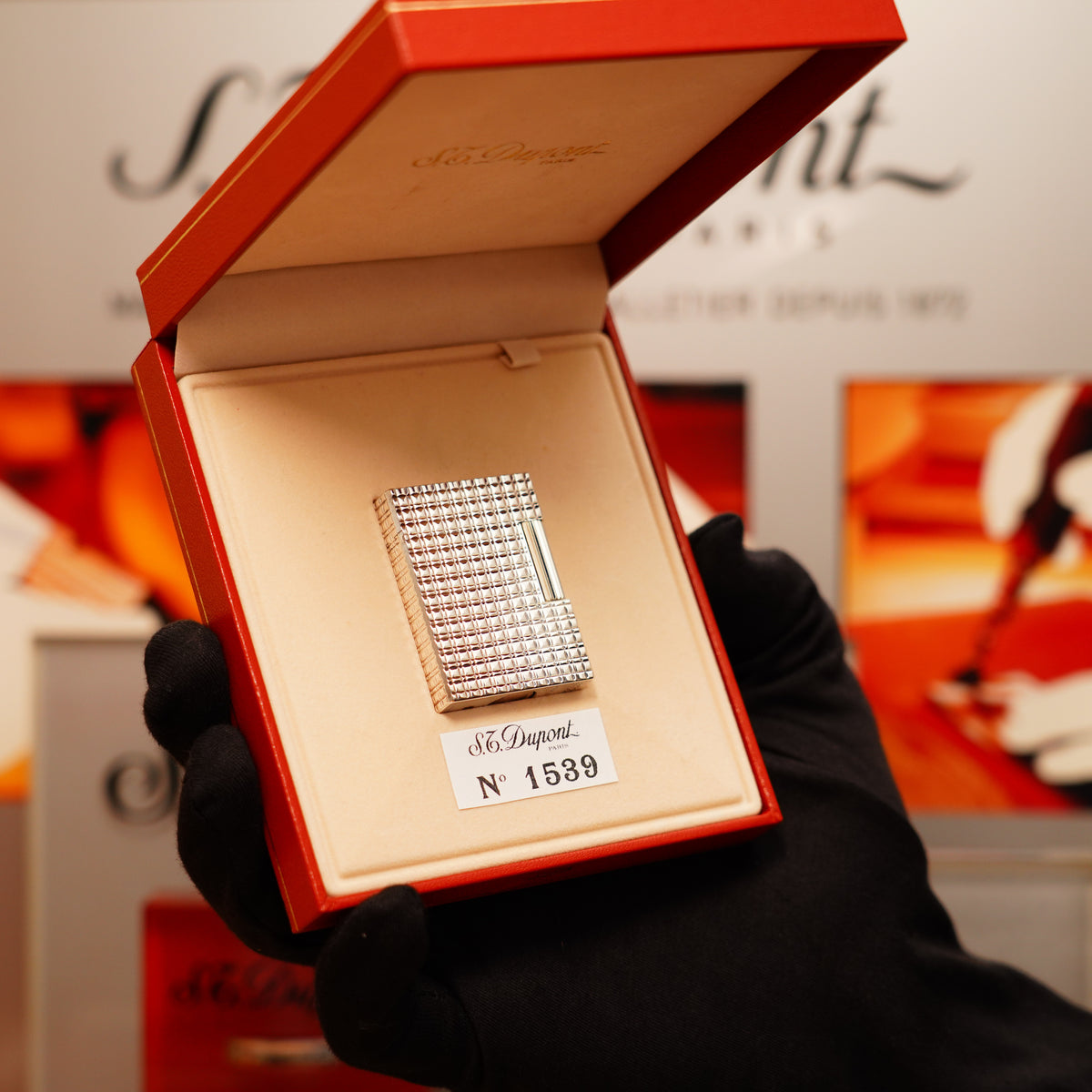A gloved hand holds an open box containing a Vintage 1990 S.T. Dupont Iconic Ligne 1 lighter in heavy silver with a rare window pattern design.