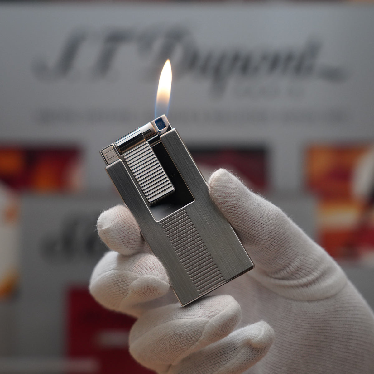A person holding up a S.T. Dupont Vintage 2000 Palladium Décor High Tech 2000s Lighter in front of a sign.