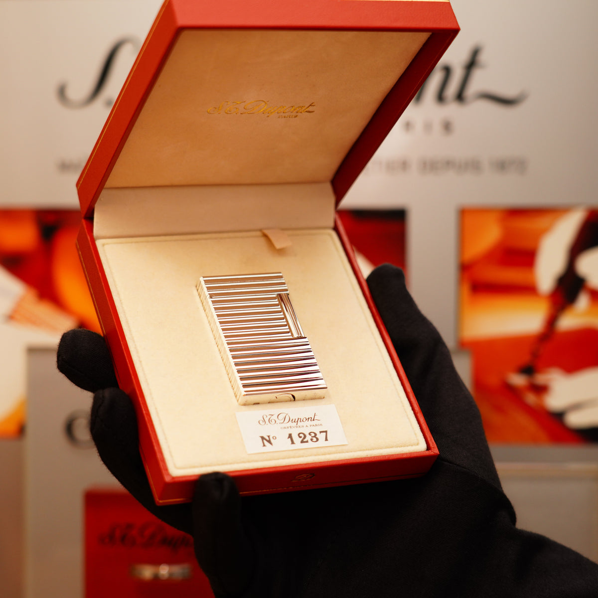 A gloved hand holds a Vintage 1990 S.T. Dupont Ligne 1 silver horizontal pattern lighter in red and beige packaging, marked with number 4287.