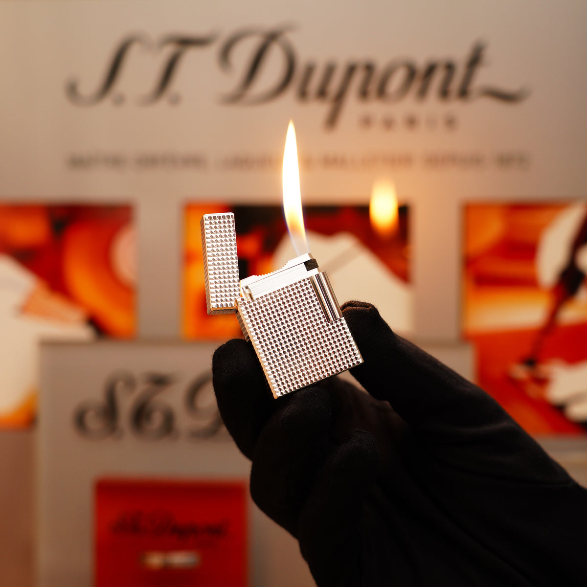 Someone holding a lit Vintage 1996 St Dupont Ligne 1 Diamond Head Pattern Lighter in Heavy Silver Finish against a blurred background with S.T. Dupont branding.