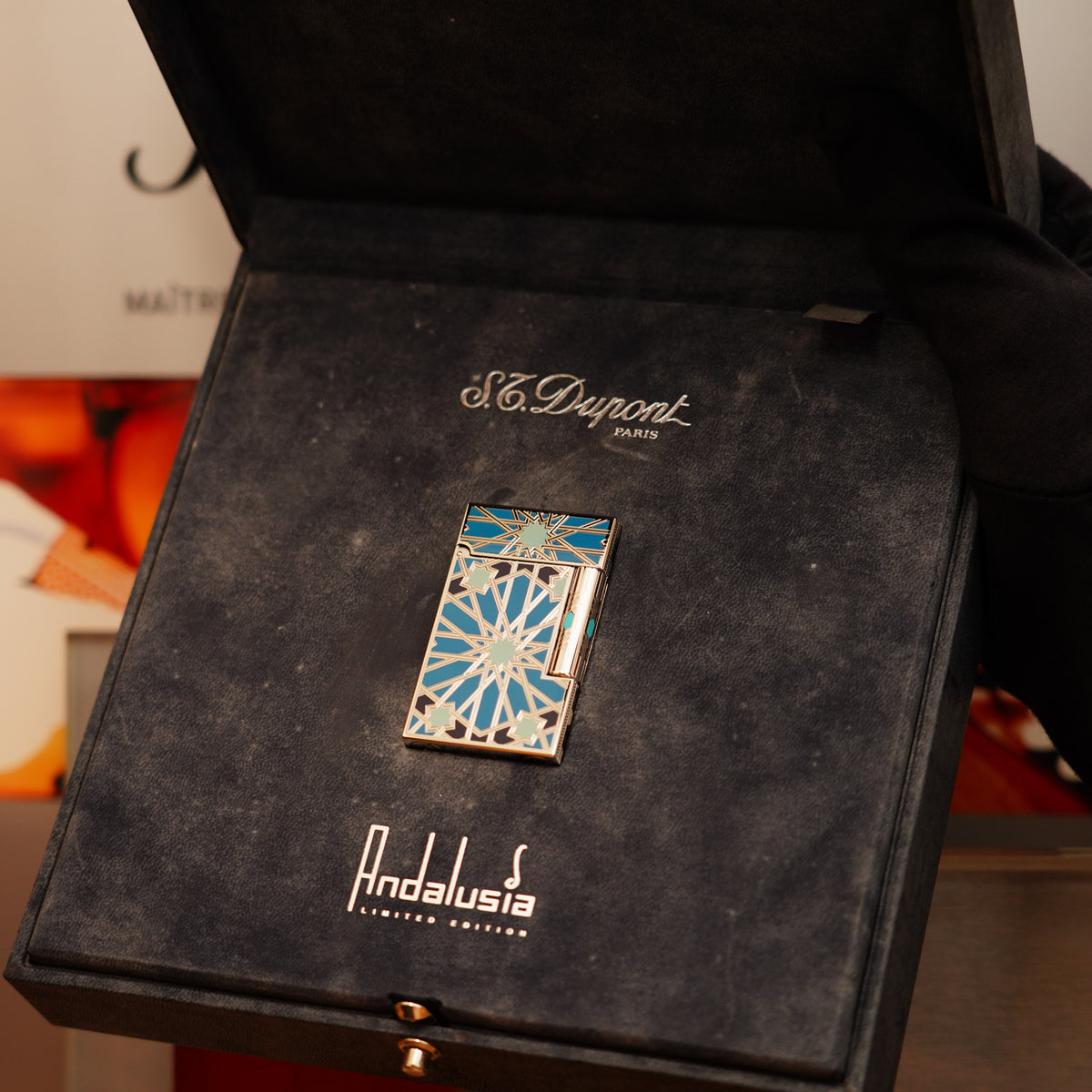 A Vintage 2003 S.T. Dupont Andalusia Limited Edition lighter in sky blue natural lacquer and platinum, featuring a geometric design, is presented in an open black box with "Andalusia" inside.