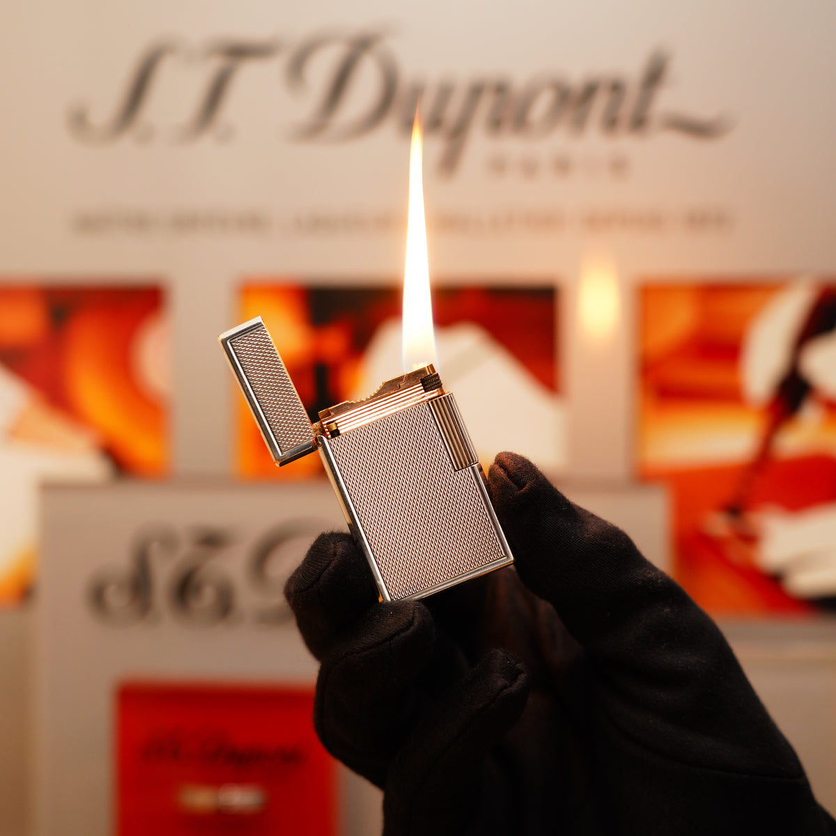 A gloved hand holds a lit lighter with the branding "S.T. Dupont" visible, showcasing the Vintage 1940 St Dupont Petrol initial version Essence Heavy Silver Finish, in extremely rare condition.