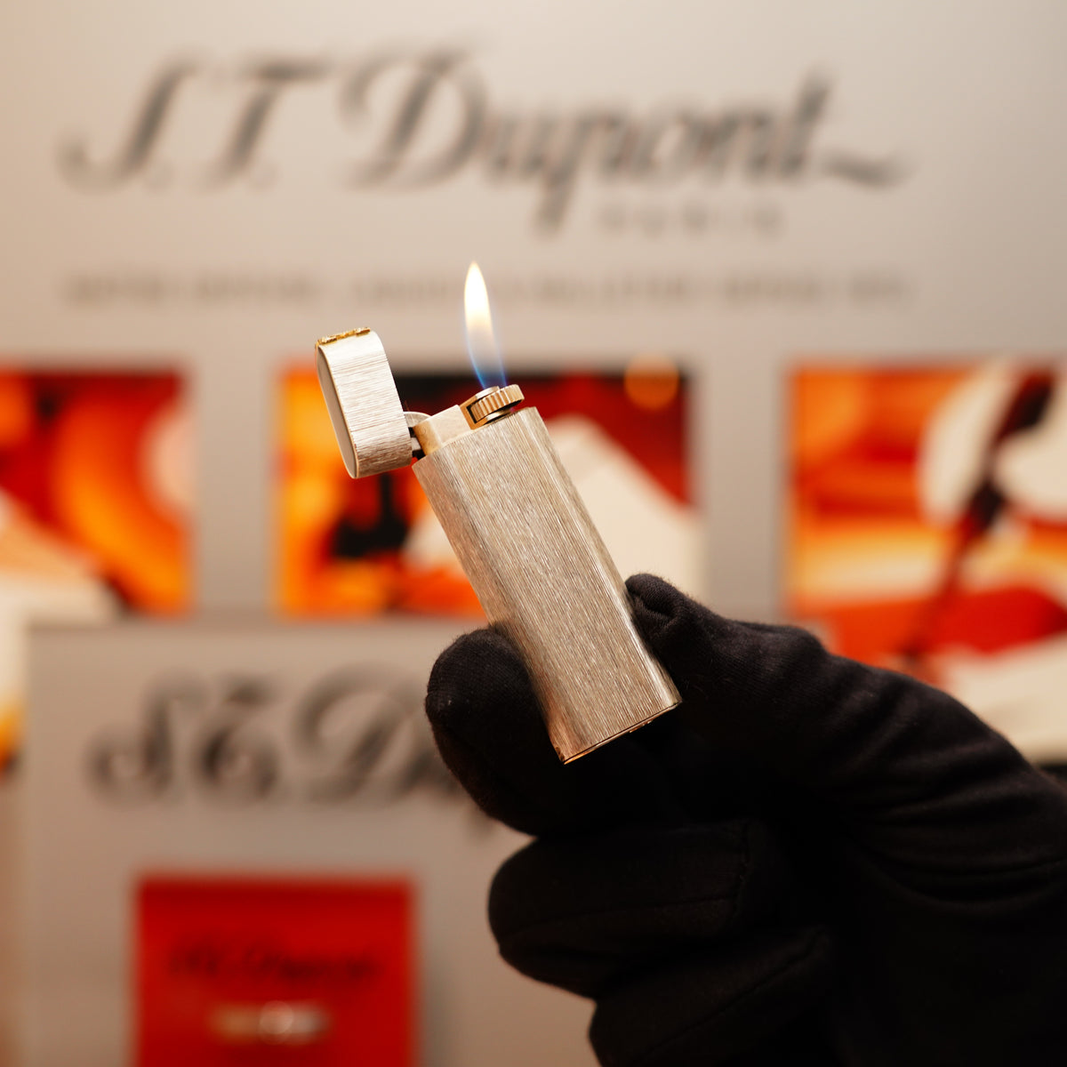 A gloved hand holds a lit Vintage 1970 Extremely Rare Cartier solid 925 sterling Double C solid 18k lighter with diamond set, against a blurred background featuring Cartier branding.