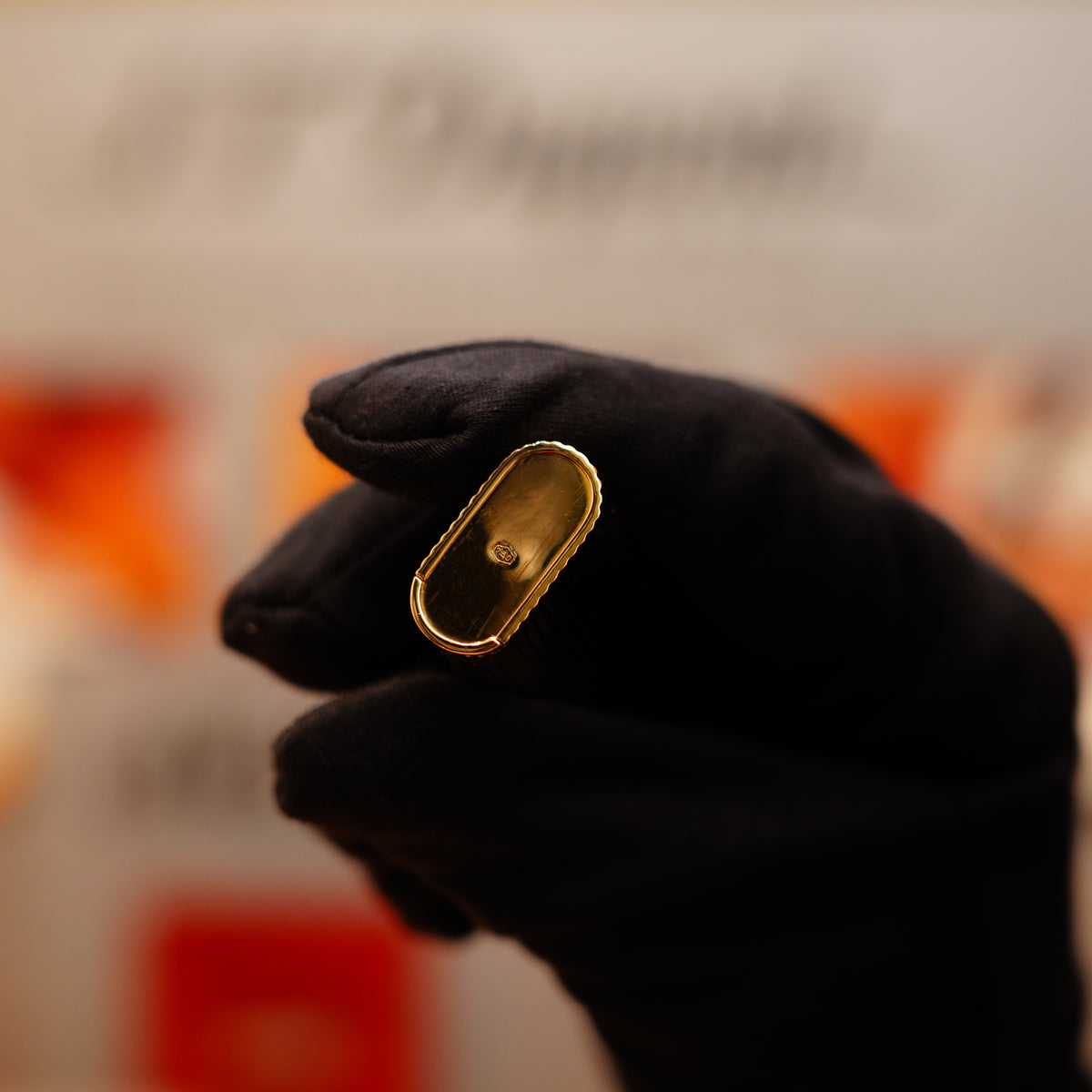 A gloved hand holds a Vintage 1970 Extremely Rare Cartier Solid 18k Gold Vertical Line Heavy Lighter against a blurred background.