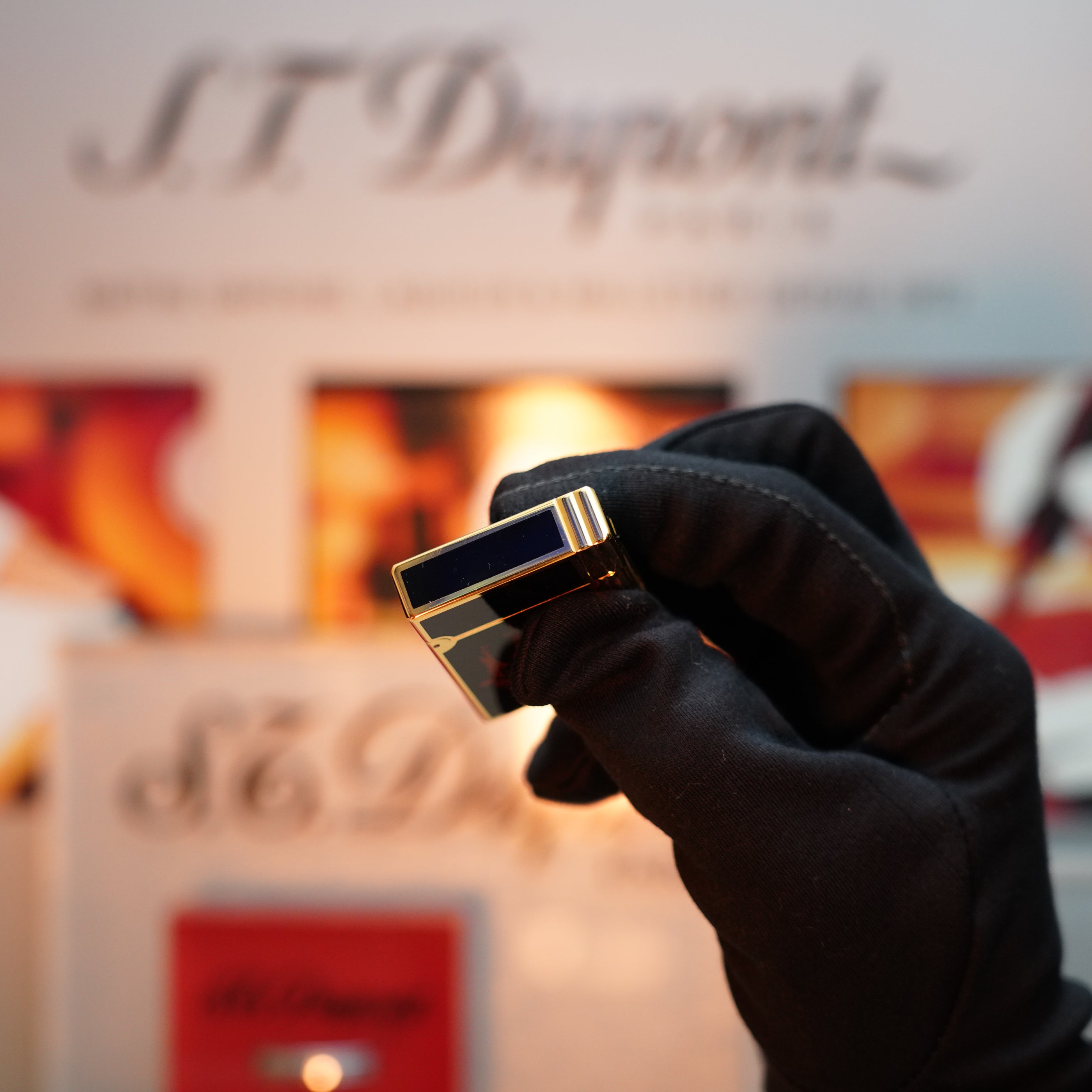 A gloved hand delicately holds a Vintage 1992 St Dupont Important 24k Gold Finish Columbus Gatsby second Limited Edition ever made Lighter, set against a blurred background showcasing the iconic S.T. Dupont logo.