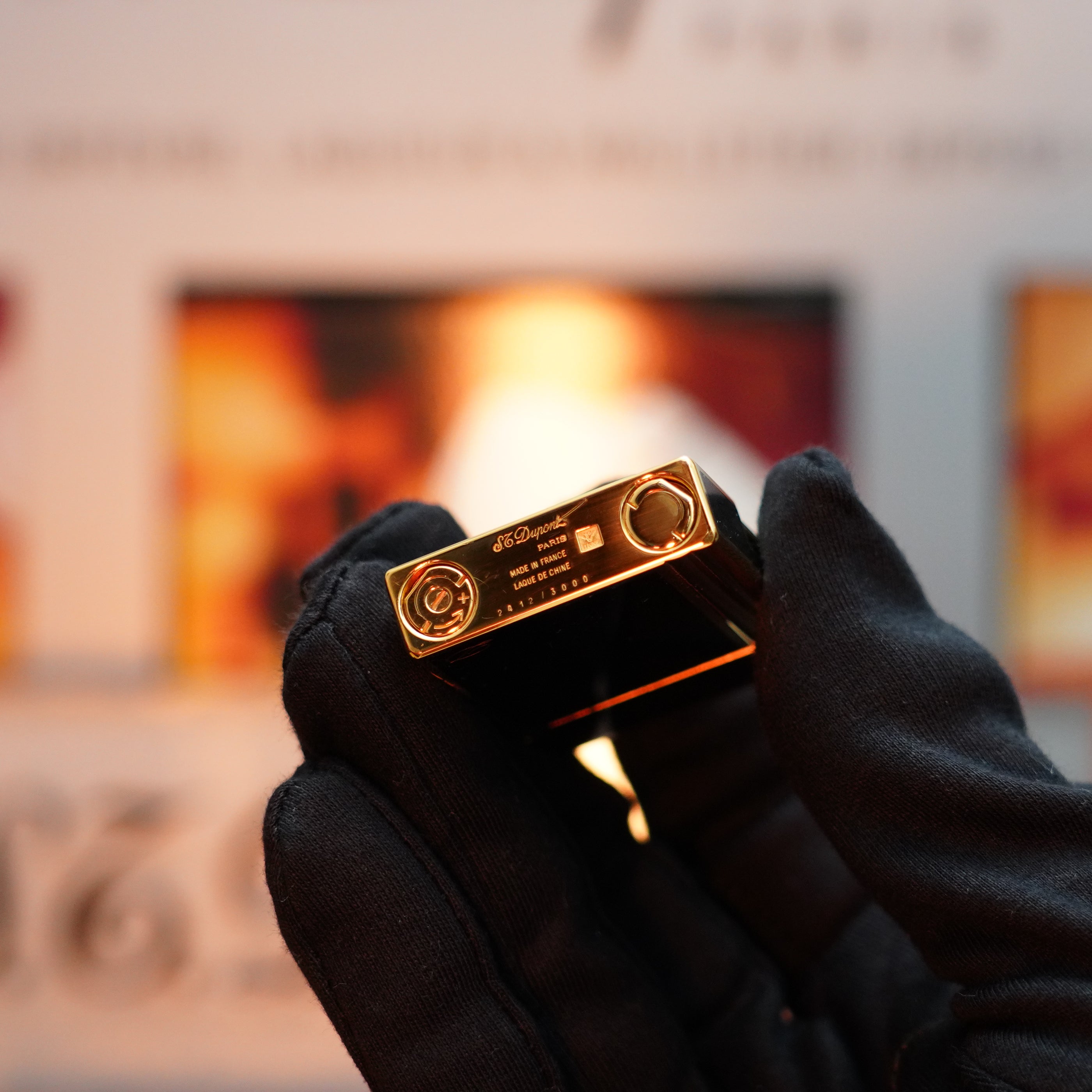 A gloved hand grasps a small, rectangular electronic device with a shiny surface and visible connectors, reminiscent of the elegance found in an S.T. Dupont Vintage 1992 Important 24k Gold Finish Colombus Gatsby second Limited Edition ever made Lighter. The blurred background adds an air of mystery, evoking thoughts of a rare, limited edition treasure.