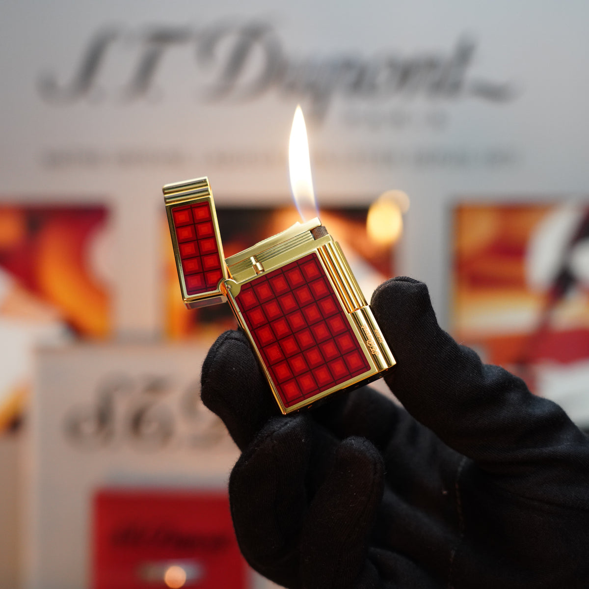 A gloved hand holds an open Vintage 1990 S.T. Dupont Limited Edition Vertigo Gatsby Ligne 2 Lighter, featuring a red grid pattern and a flame flickering above its vintage design accented with a 24k gold finish.