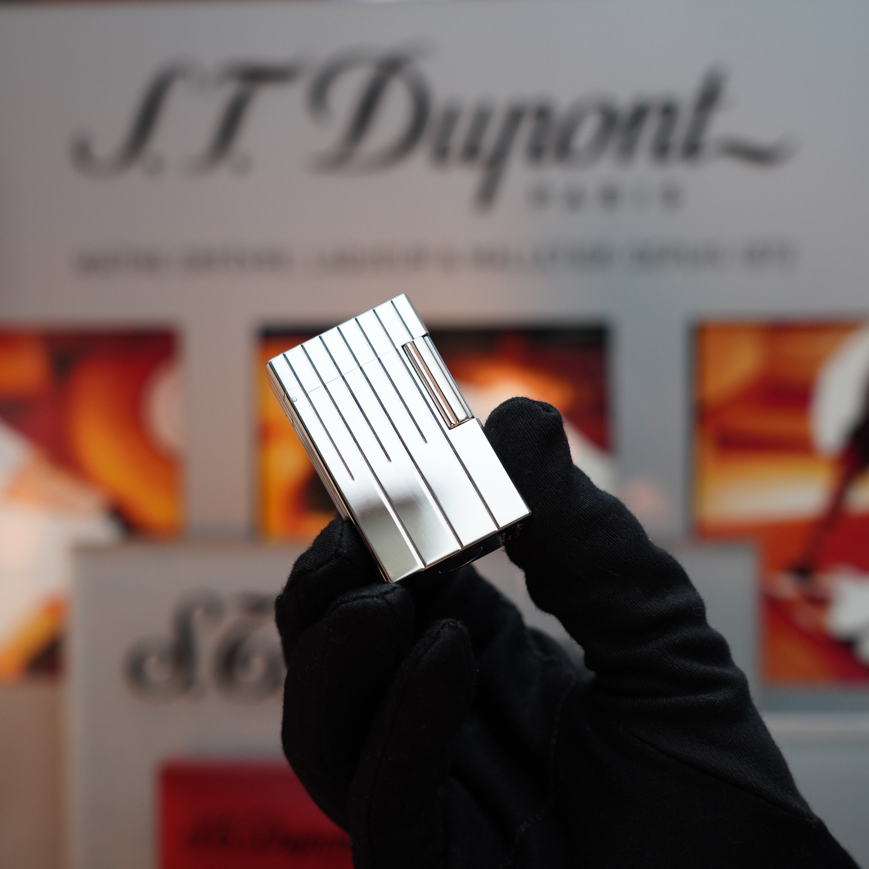 A gloved hand holds a Vintage 1999 S.T. Dupont Rare Perspective 2000 Palladium Limited Edition Ligne 1 Lighter, set against a blurred background showcasing the S.T. Dupont logo.