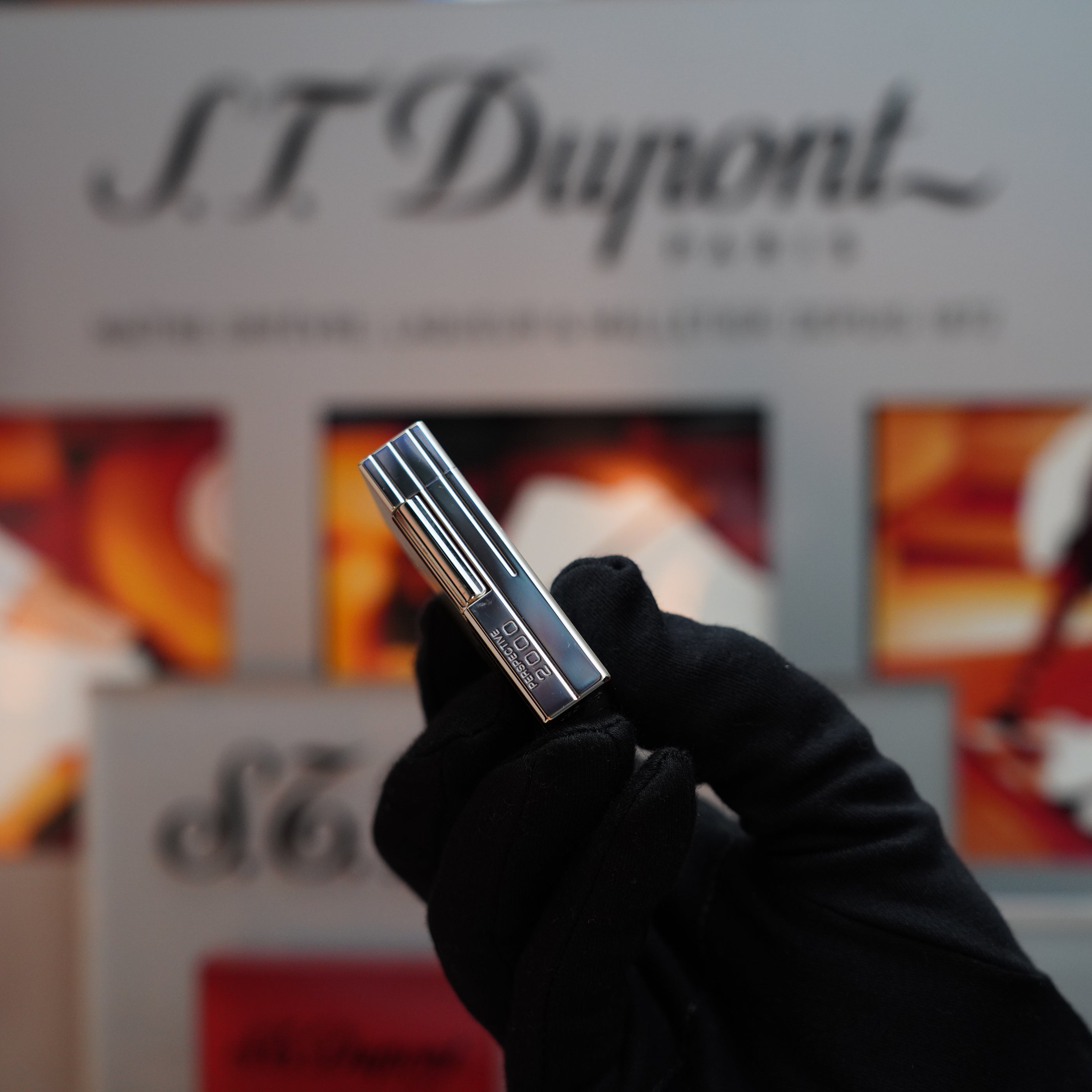 A gloved hand holds a Vintage 1999 S.T. Dupont Limited Edition Ligne 1 Palladium lighter, positioned against a blurred display of the brand.