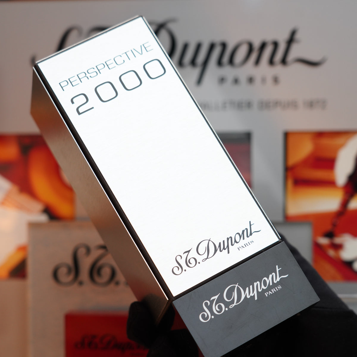 A person elegantly holds a rectangular box from the Vintage 1999 S.T. Dupont Rare Perspective 2000 Palladium Limited Edition Ligne 1 Lighter collection, reminiscent of the timeless sophistication found in S.T. Dupont's designs.
