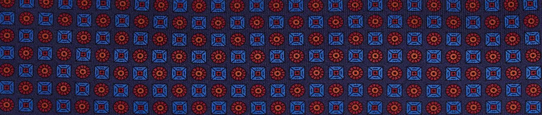 Close-up of a fabric with a repeating geometric pattern of red circles inside squares and blue squares on a dark blue background.