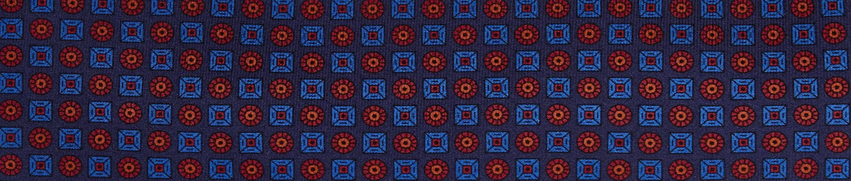 Close-up of a fabric with a repeating geometric pattern of red circles inside squares and blue squares on a dark blue background.