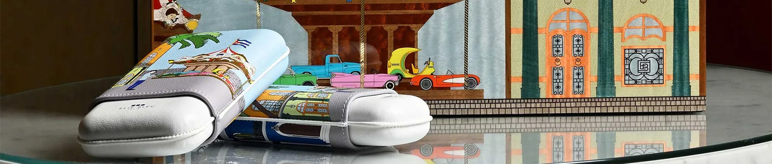 Colorful slide sandals with graphic design placed in front of a detailed illustration on a box.