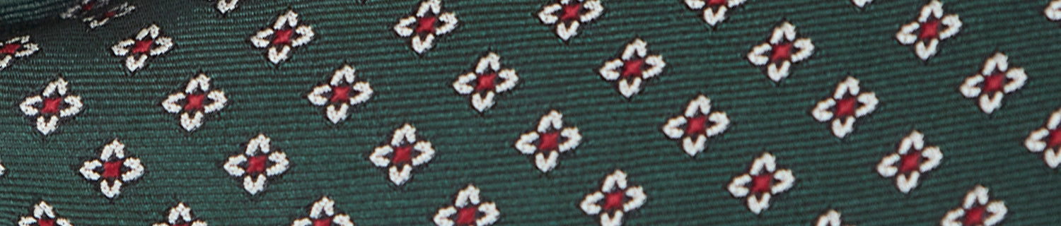 Close-up of a dark green fabric with a repeated pattern of red and white geometric shapes.