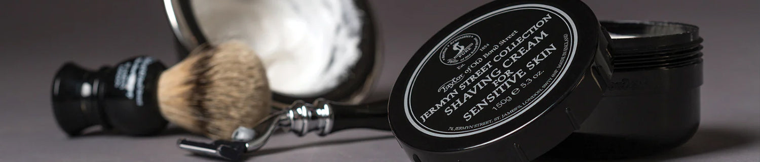 Close-up of shaving cream, a brush, and a shaving bowl arranged on a surface.