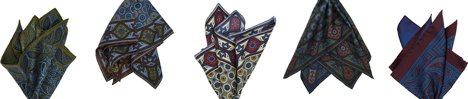 Five folded pocket squares in various paisley and geometric patterns, laid out in a row.
