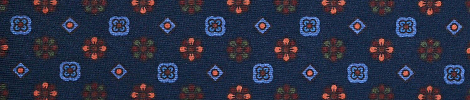 Patterned fabric featuring small red and blue geometric shapes on a dark blue background.