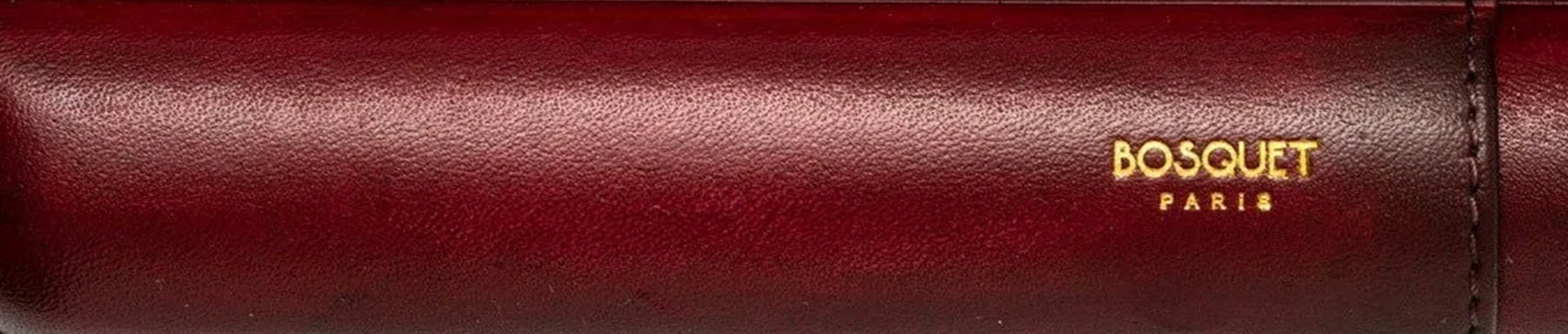 Close-up of a red leather item with the gold embossed text "BOSQUET PARIS" on the right side.