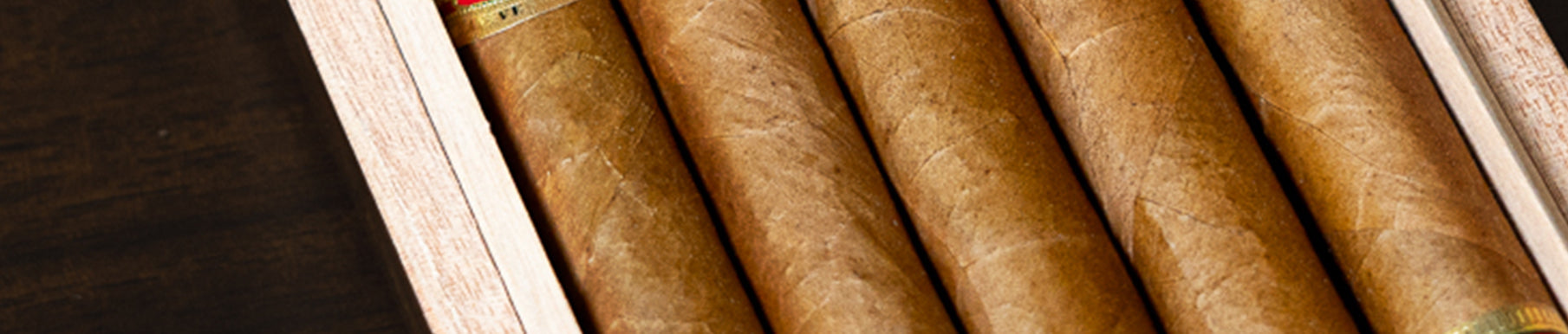 Close-up view of several brown cigars arranged in a wooden cigar box.
