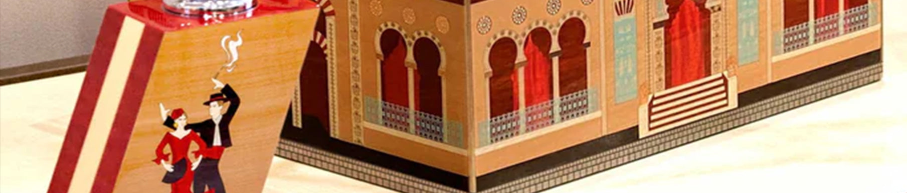 A close-up of a decorative object resembling a blue building facade with arched windows and doors. A smaller item with a palm tree design is positioned in front.