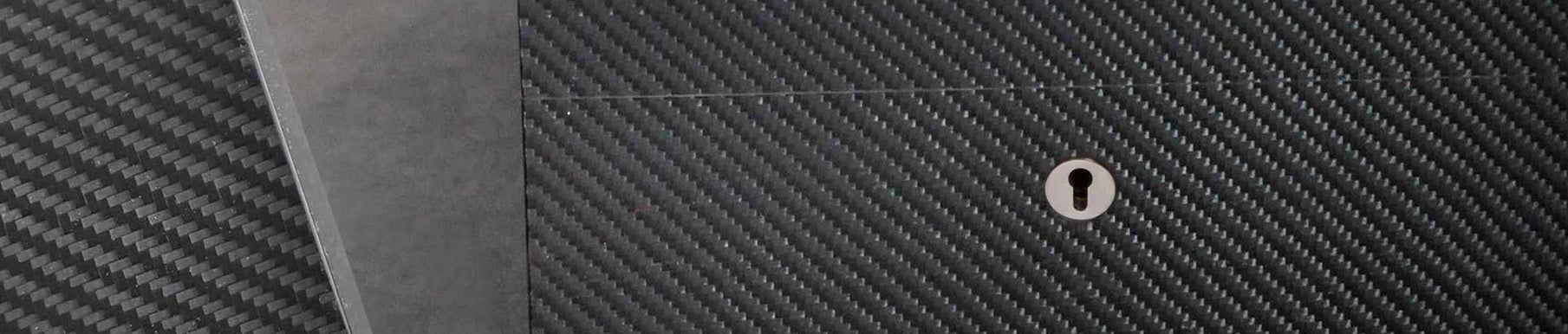 Close-up of a carbon fiber surface with a keyhole and a section of matte gray metal overlapping on the left side.