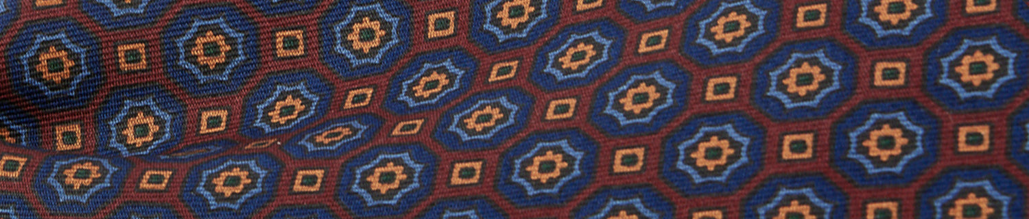 Close-up of a fabric with a geometric pattern featuring blue hexagons and orange diamonds on a red background.