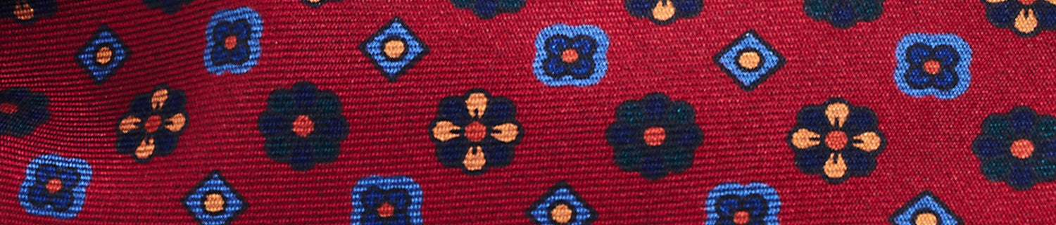 A red fabric with a pattern of blue and black floral and geometric shapes.