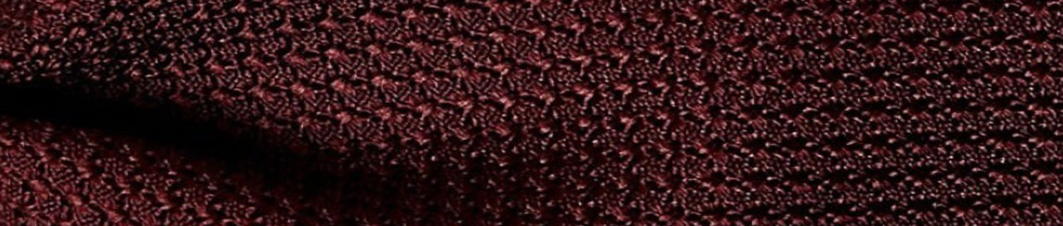 Close-up of textured dark red fabric with a woven pattern.