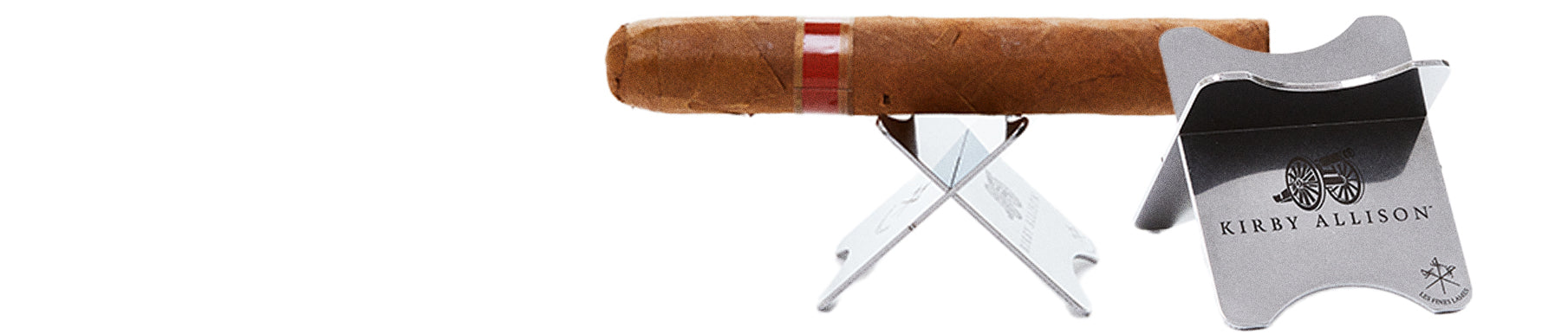 A cigar rests on a metal stand with "Kirby Allison" engraved on it.