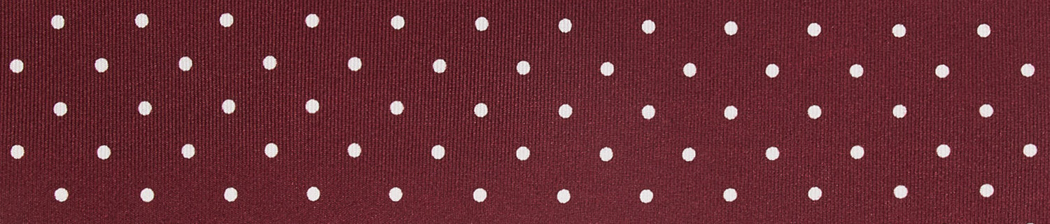 Maroon fabric with evenly spaced white polka dots in rows.