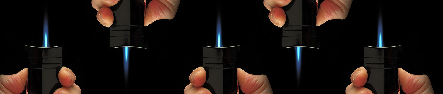 Hands holding and igniting black torch lighters against a black background, with visible blue flames.