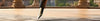 Close-up of a fountain pen tip touching a stone floor, with architectural columns and greenery in the blurred background.