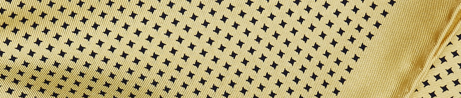 Close-up of a yellow fabric with a pattern of small black diamonds.