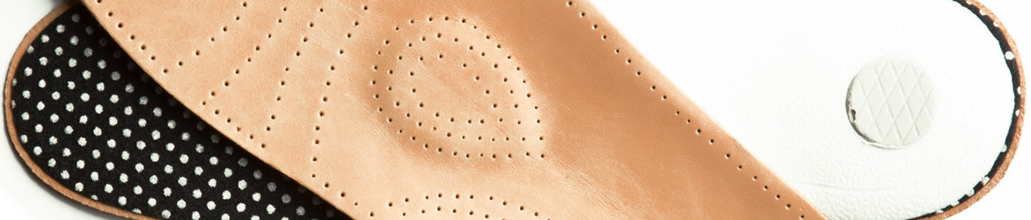 A pair of black shoes and a brush on a black surface.