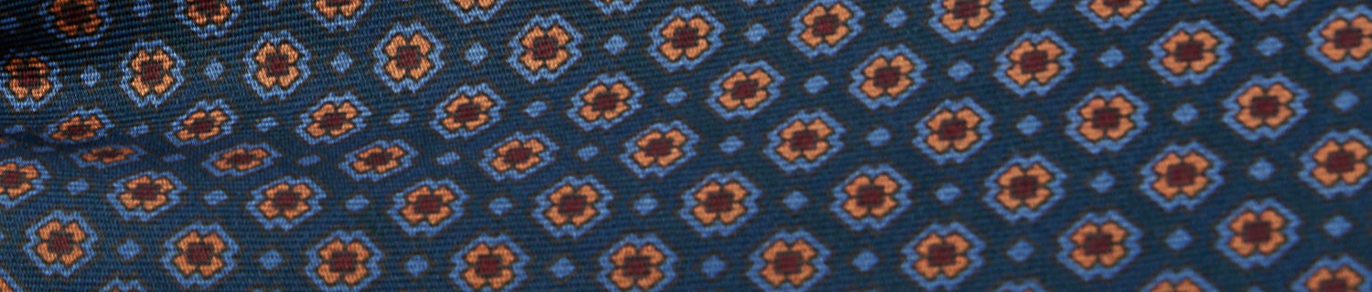 Close-up of fabric with a repeating geometric pattern featuring orange and blue shapes on a dark background.