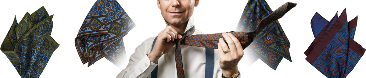 A man in a white shirt and suspenders tying a patterned brown tie, surrounded by four distinct paisley pocket squares.