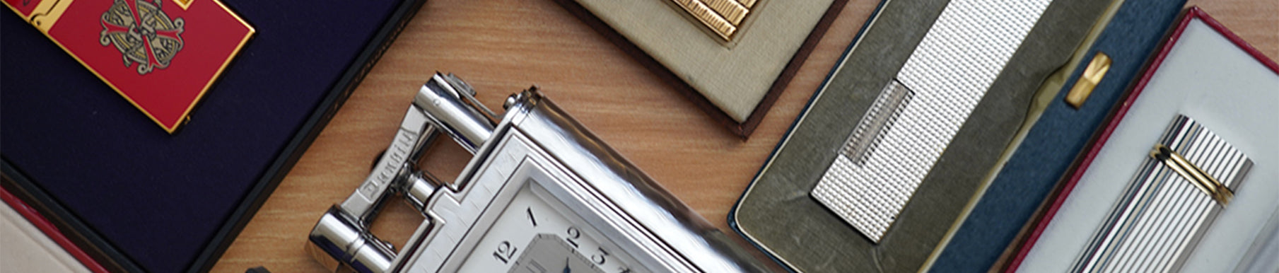A collection of luxury lighters and cases displayed on a wooden surface.