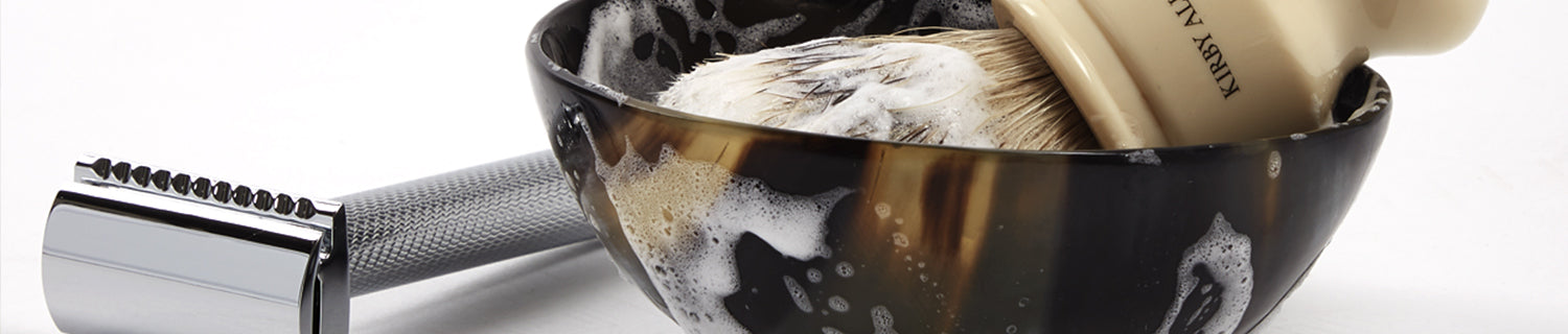 A shaving brush and shaving cream in a cup.