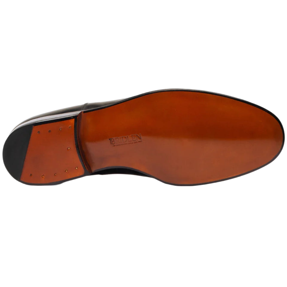 The image displays a Punch Cap Oxford dress shoe by Bridlen, made with polished box calf leather and featuring a rich brown sole with small nails around the heel, ideal for formal occasions.