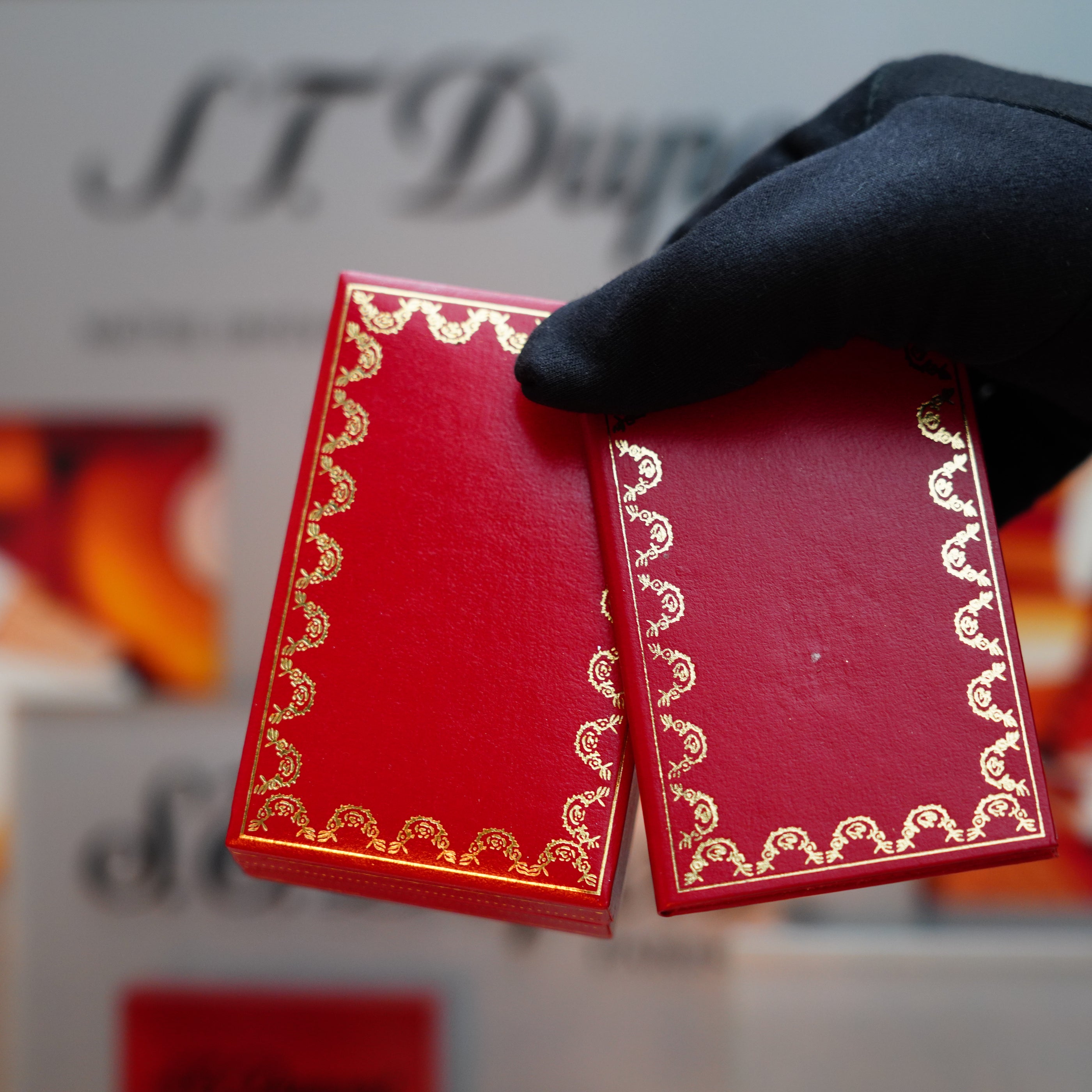 A hand holding red cards, reminiscent of the unique horizontal line design found on a Vintage 1985 Cartier Burgundy Red 24k Gold Lacquer Le Must Lighter.