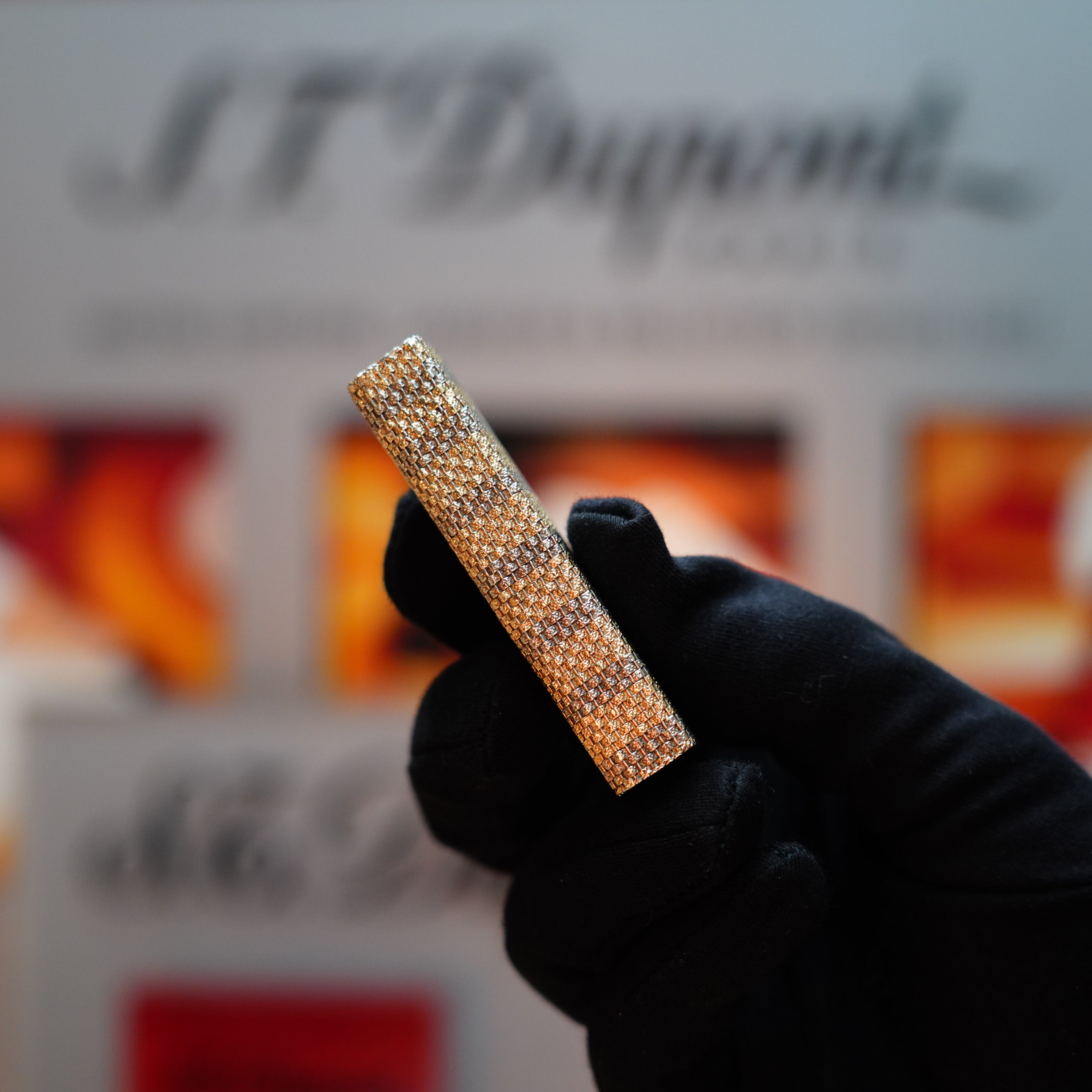 A gloved hand holds a unique Vintage 1978 Cartier Rare Pentagon Lighter from the Basket Series, its pentagonal form crafted from solid 18k gold and distinguished by the 750 hallmarks, set against a blurred background.