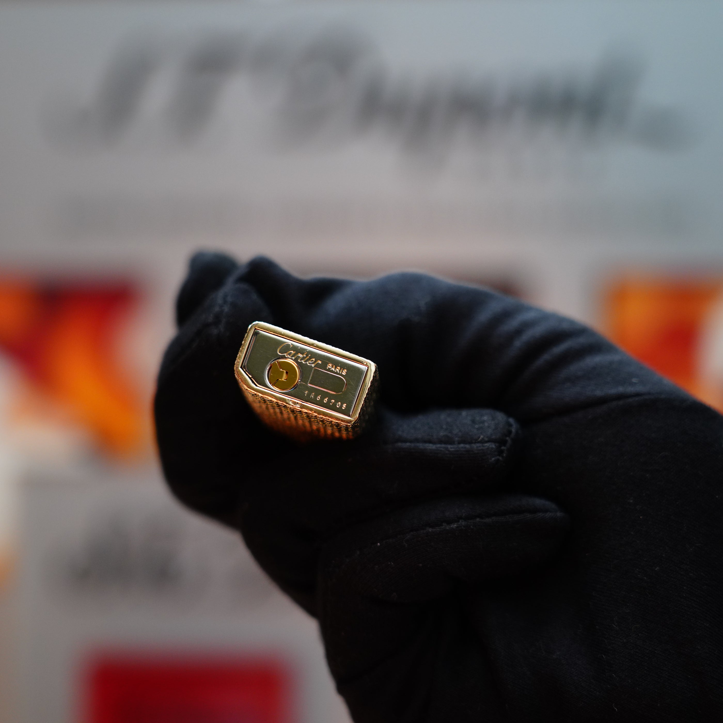 A gloved hand holds a Vintage 1978 Cartier Rare Pentagon Solid 18k Gold Jacket Basket Lighter, adorned with the Cartier logo and the 750 hallmarks visible on its top.