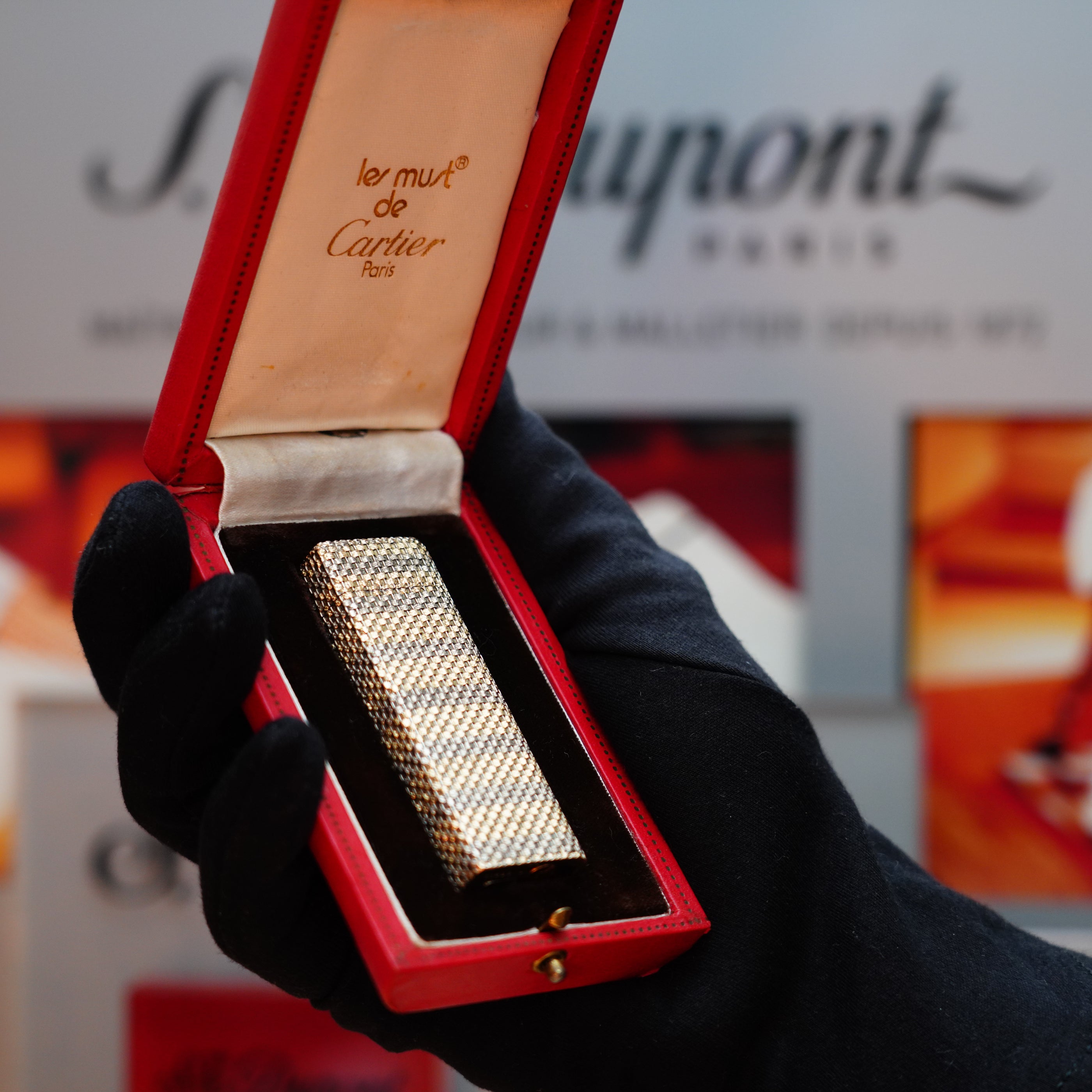 A gloved hand holds an open red box, revealing a Vintage 1978 Cartier Rare Pentagon Solid 18k Gold Jacket Basket with 750 hallmarks Lighter.