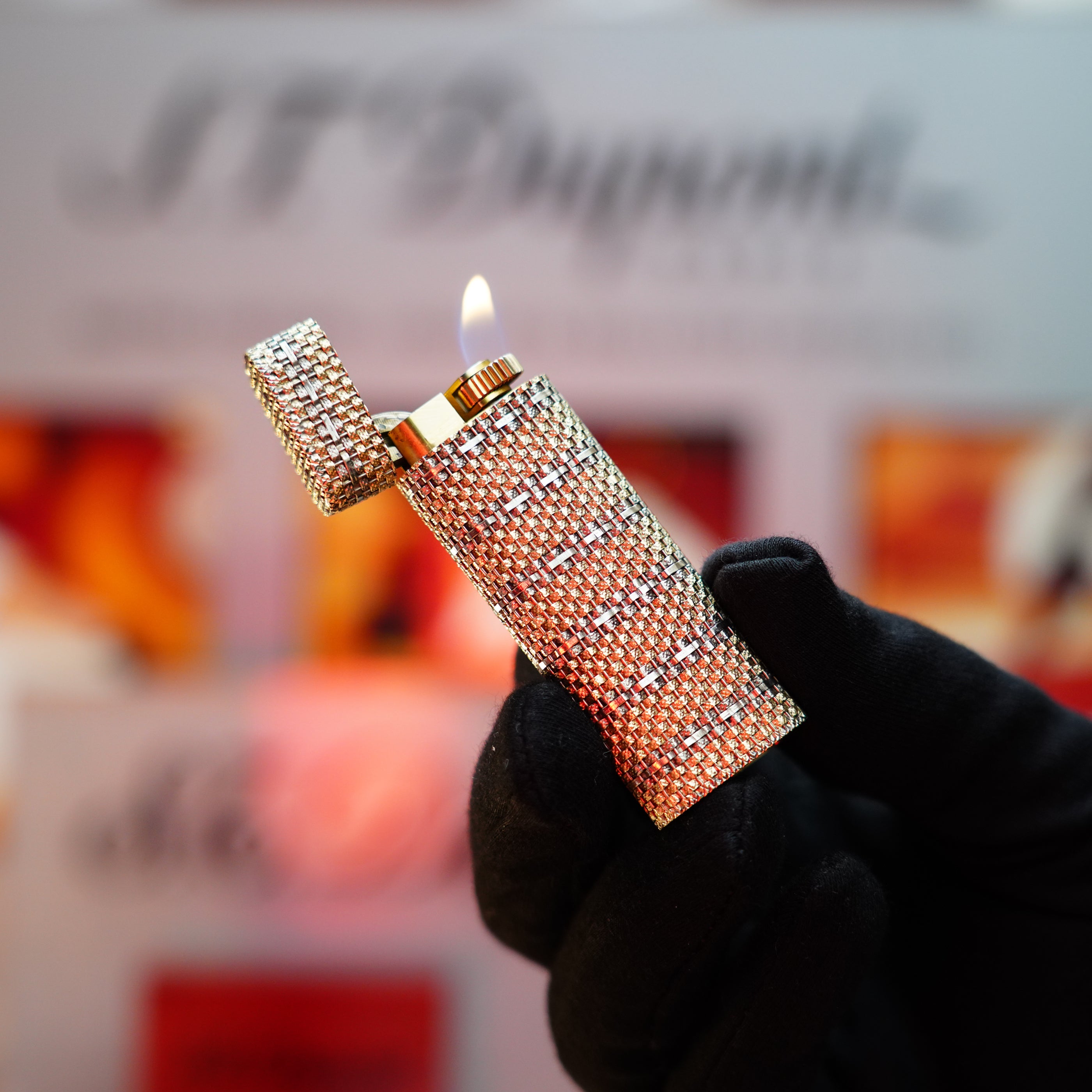 A person wearing a black glove holds an open Vintage 1982 Cartier Solid 18k Gold Jacket Basket lighter, its shimmering design glinting as a visible flame dances above the rare collectible.