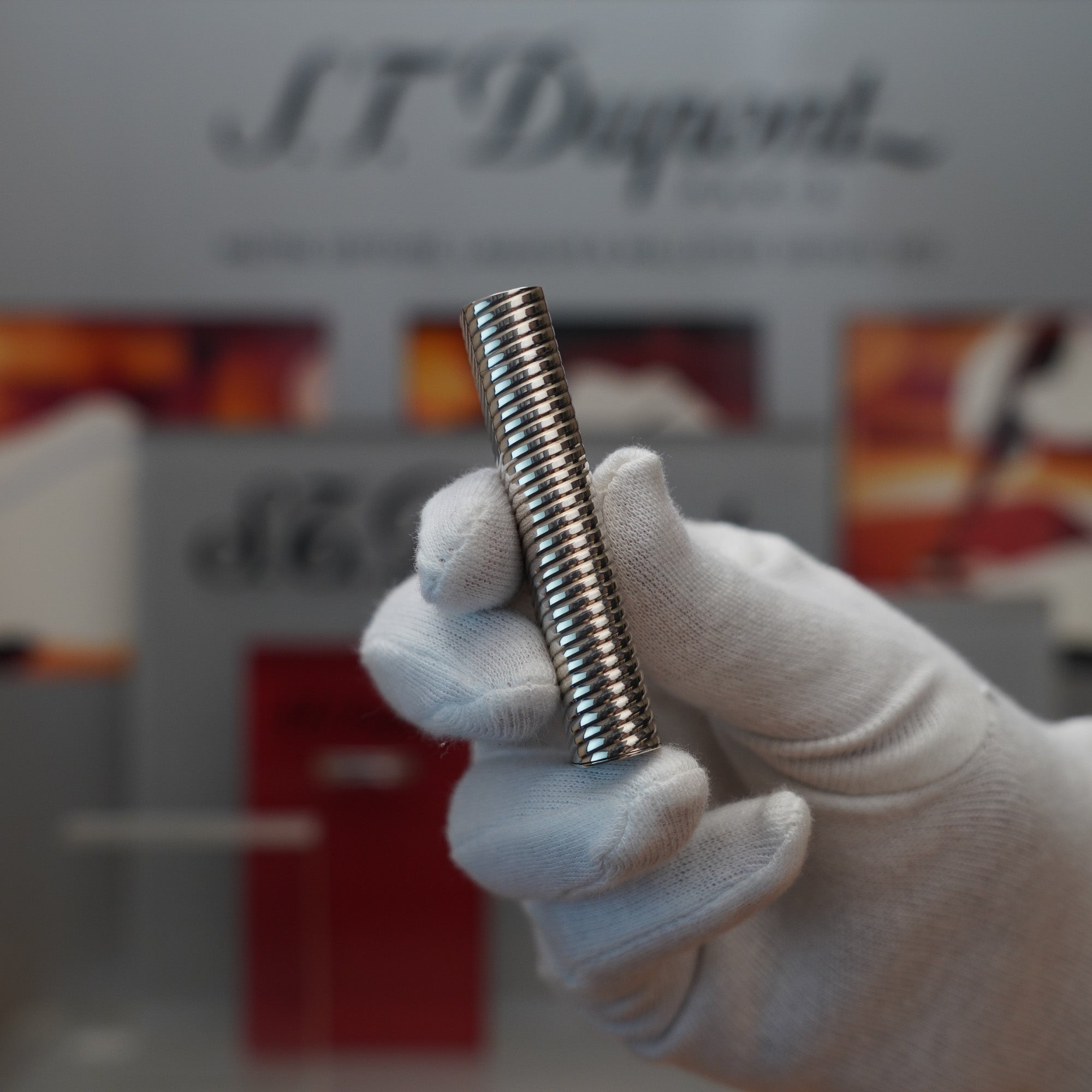 A person is holding a Vintage 1980 Cartier Solid Silver 925 Lighter Factory Argent ( Torsade ) in front of a display.