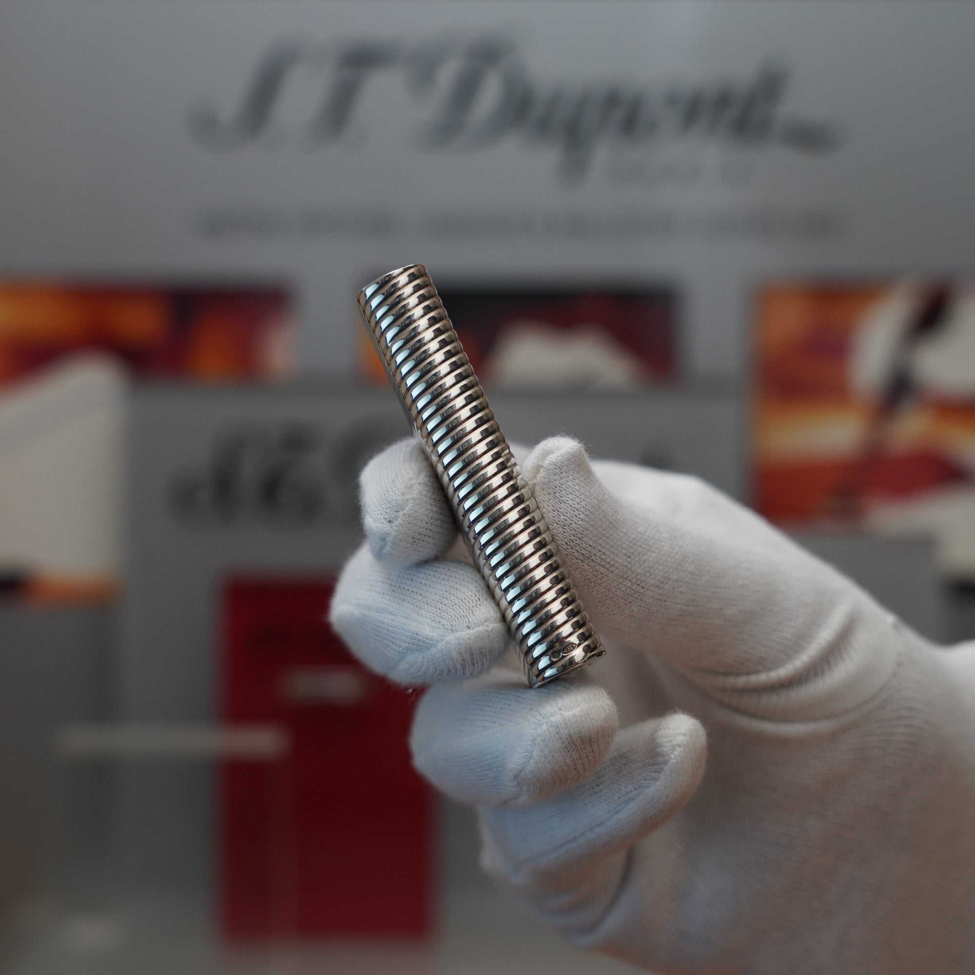 A person is holding a Vintage 1980 Cartier Solid Silver 925 Lighter Factory Argent ( Torsade ) metal rod in front of a display.