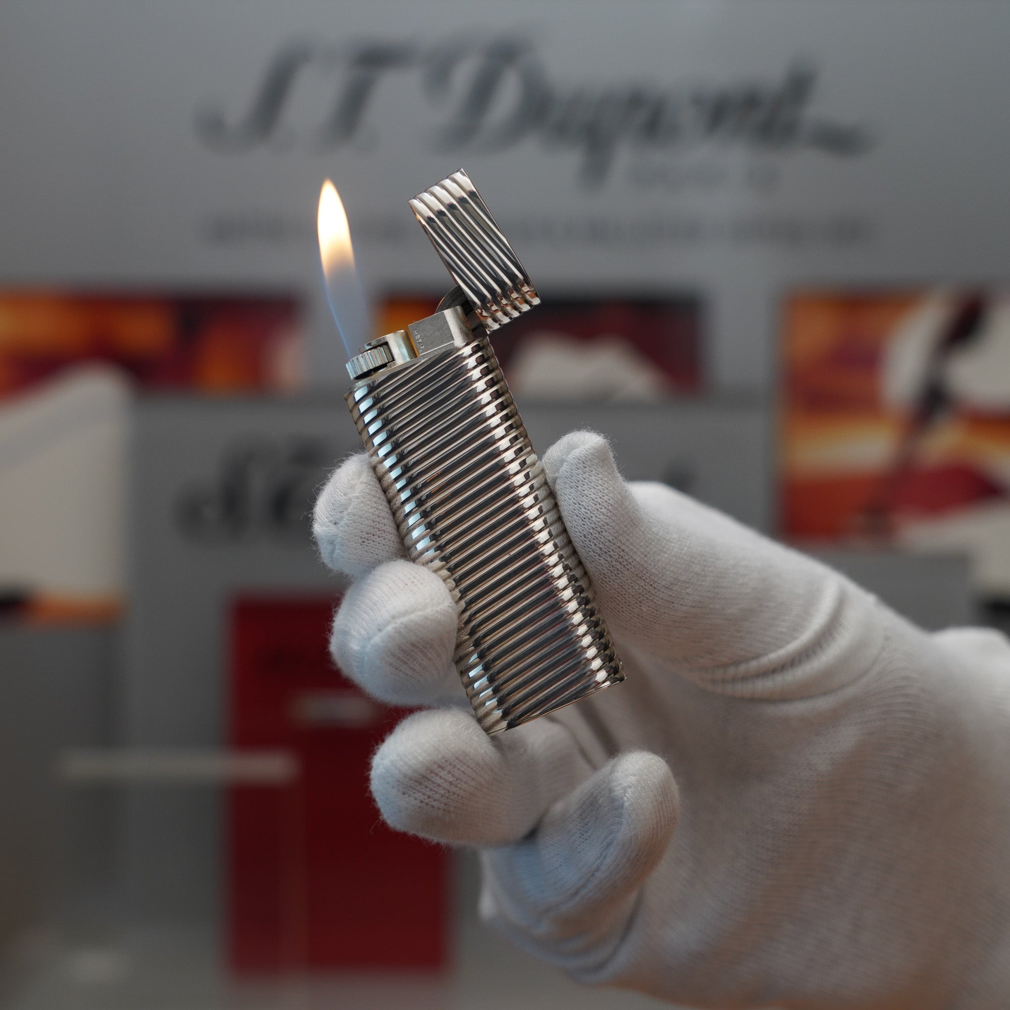 A vintage hand holding a Cartier Solid Silver 925 Lighter Factory Argent ( Torsade ) in front of a display.