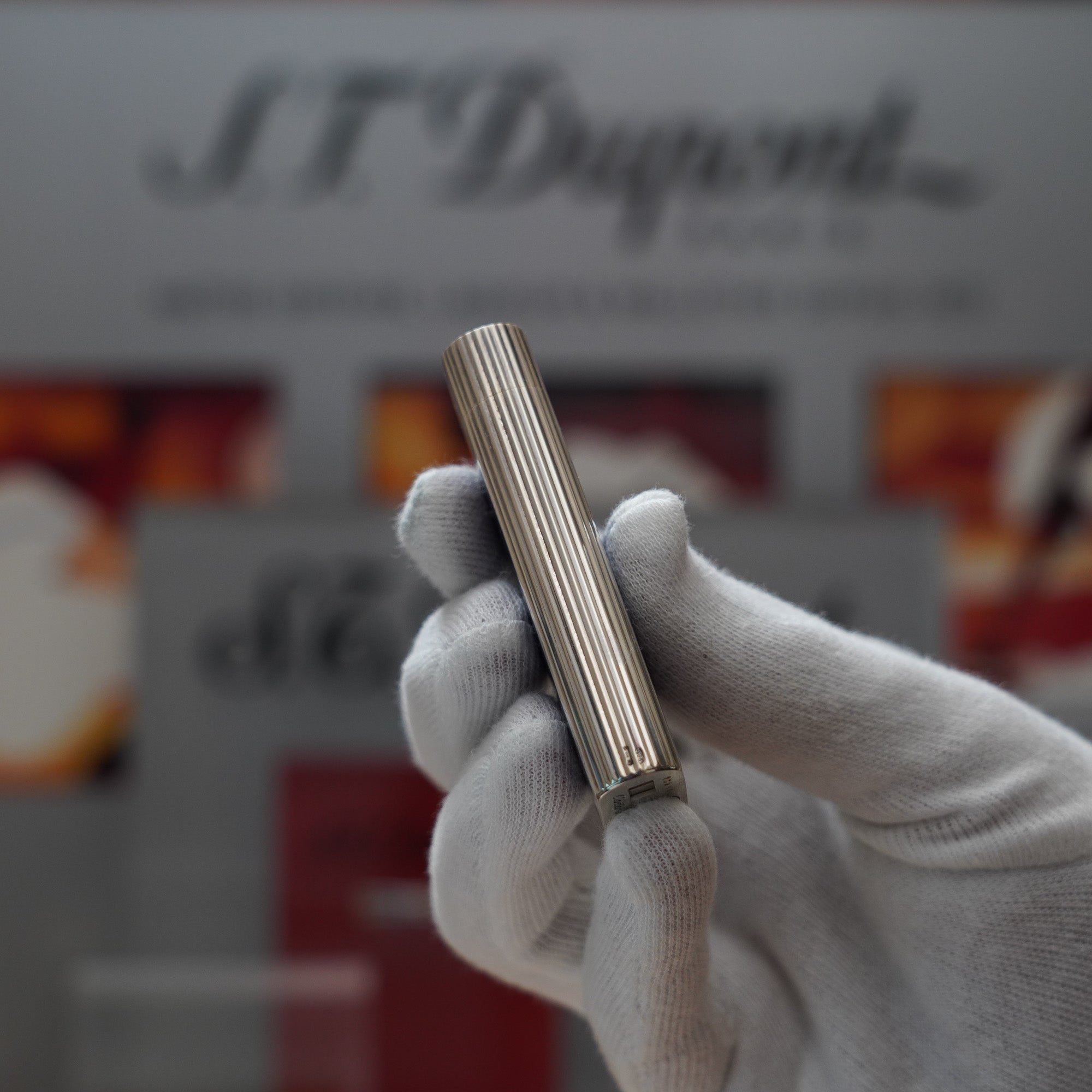 A person is holding a Cartier Vintage 1980 Cartier Solid Silver 925 Blue Enamel Factory ( Smalto Blu ) tube in front of a sign.